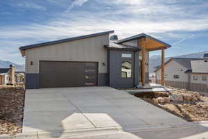 View of front of house with a mountain view, driveway, a garage, board and batten siding, and a metal roof