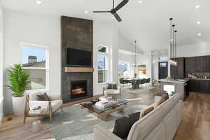 Living area featuring high vaulted ceiling, a fireplace, recessed lighting, light wood-type flooring, and a ceiling fan
