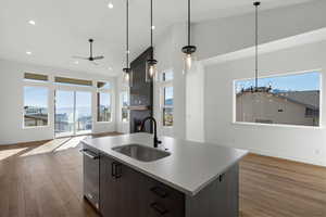Kitchen with ceiling fan, open floor plan, dark brown cabinets, high vaulted ceiling, and a kitchen island with sink