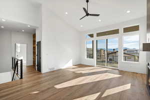 Unfurnished living room with light wood-style floors, high vaulted ceiling, a ceiling fan, and recessed lighting