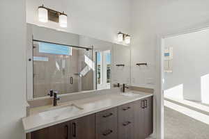 Full bath featuring double vanity, a shower stall, and light carpet