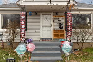 Property entrance with a shingled roof and covered porch