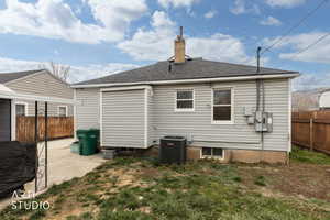 Back of property with a chimney, a patio, and a shingled roof