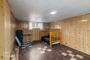 Bedroom with dark floors, wood walls, and a textured ceiling