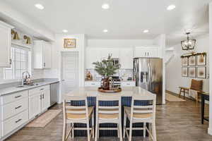 Kitchen with white cabinetry, a kitchen bar, stainless steel appliances, a kitchen island, and recessed lighting