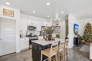 Kitchen with light stone countertops, appliances with stainless steel finishes, white cabinetry, backsplash, and recessed lighting