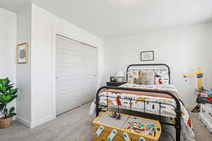 Bedroom with light colored carpet and a closet