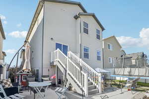 Rear view of property featuring a trampoline, a patio, stairway, stucco siding, and a residential view