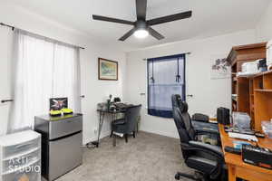 Office space with light carpet and a ceiling fan
