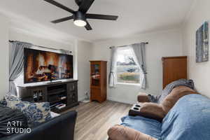 Living area featuring wood finished floors, crown molding, and ceiling fan