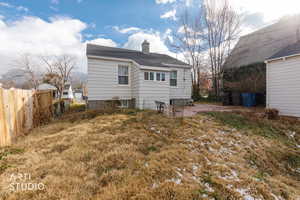 Rear view of house featuring a chimney and a shingled roof