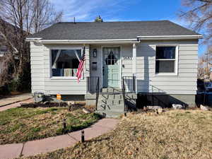 View of front of home featuring a shingled roof, a chimney, and a front lawn