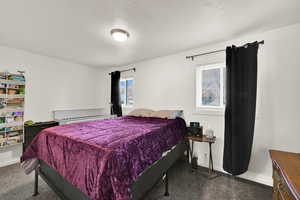 Carpeted bedroom featuring baseboards and a textured ceiling