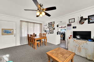 Carpeted dining space featuring crown molding, arched walkways, ceiling fan, and a textured ceiling