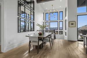 Dining space with a chandelier, light wood-type flooring, plenty of natural light, recessed lighting, and a towering ceiling