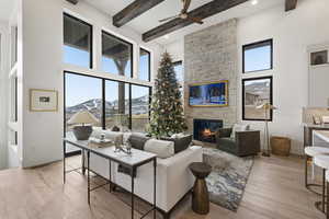 Living area featuring light wood-style flooring, healthy amount of natural light, a large fireplace, a high ceiling, and ceiling fan