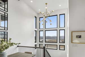 Staircase with a chandelier, a high ceiling, recessed lighting, and healthy amount of natural light