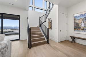 Stairway with healthy amount of natural light, wood finished floors, a high ceiling, and a mountain view