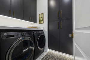 Laundry area with cabinet space, washer and dryer, and light marble finish floors