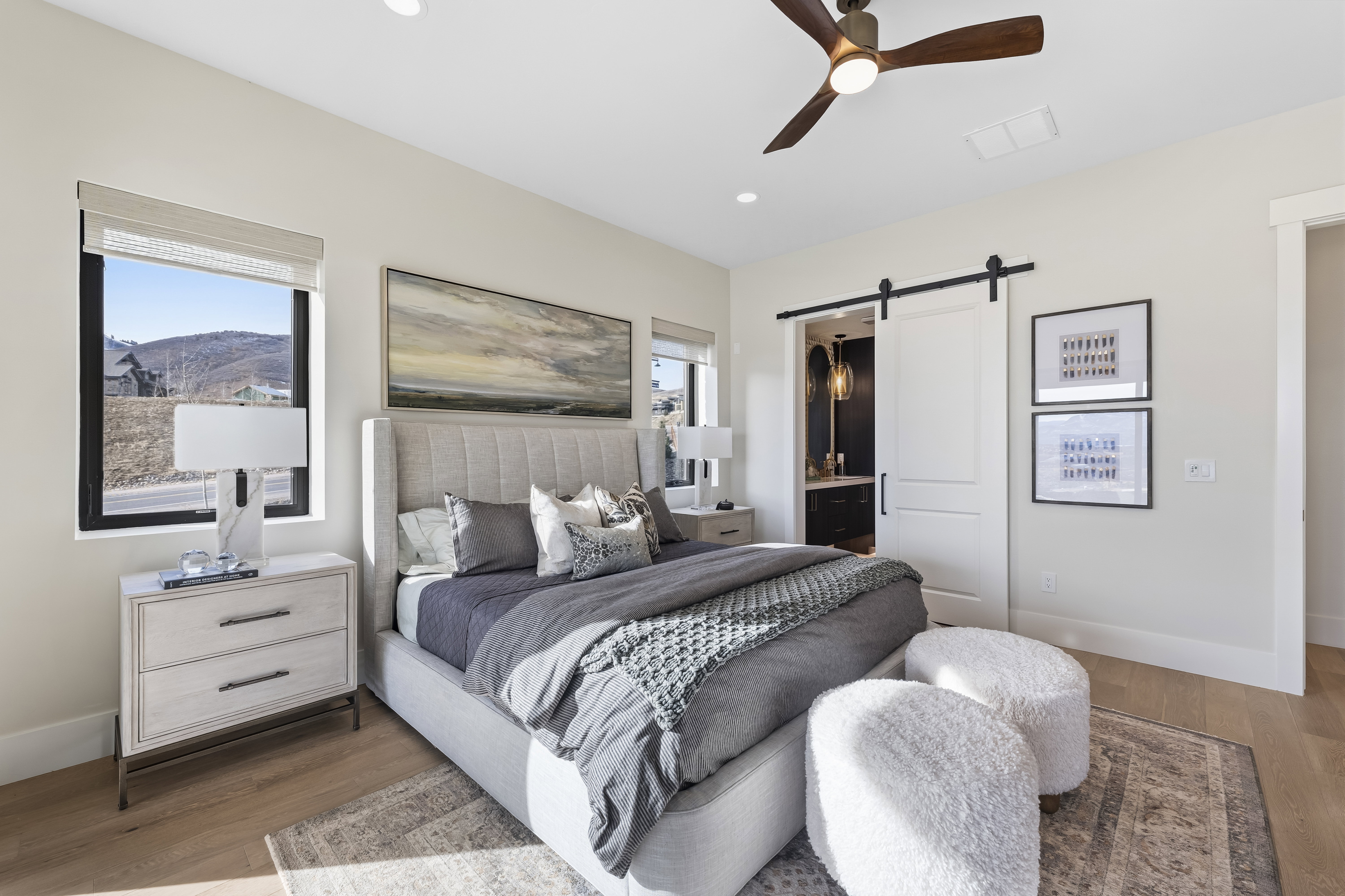 Bedroom featuring a barn door, light wood-style floors, ensuite bath, multiple windows, and recessed lighting