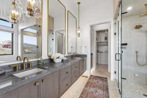 Full bathroom with double vanity, a shower stall, a chandelier, and a spacious closet