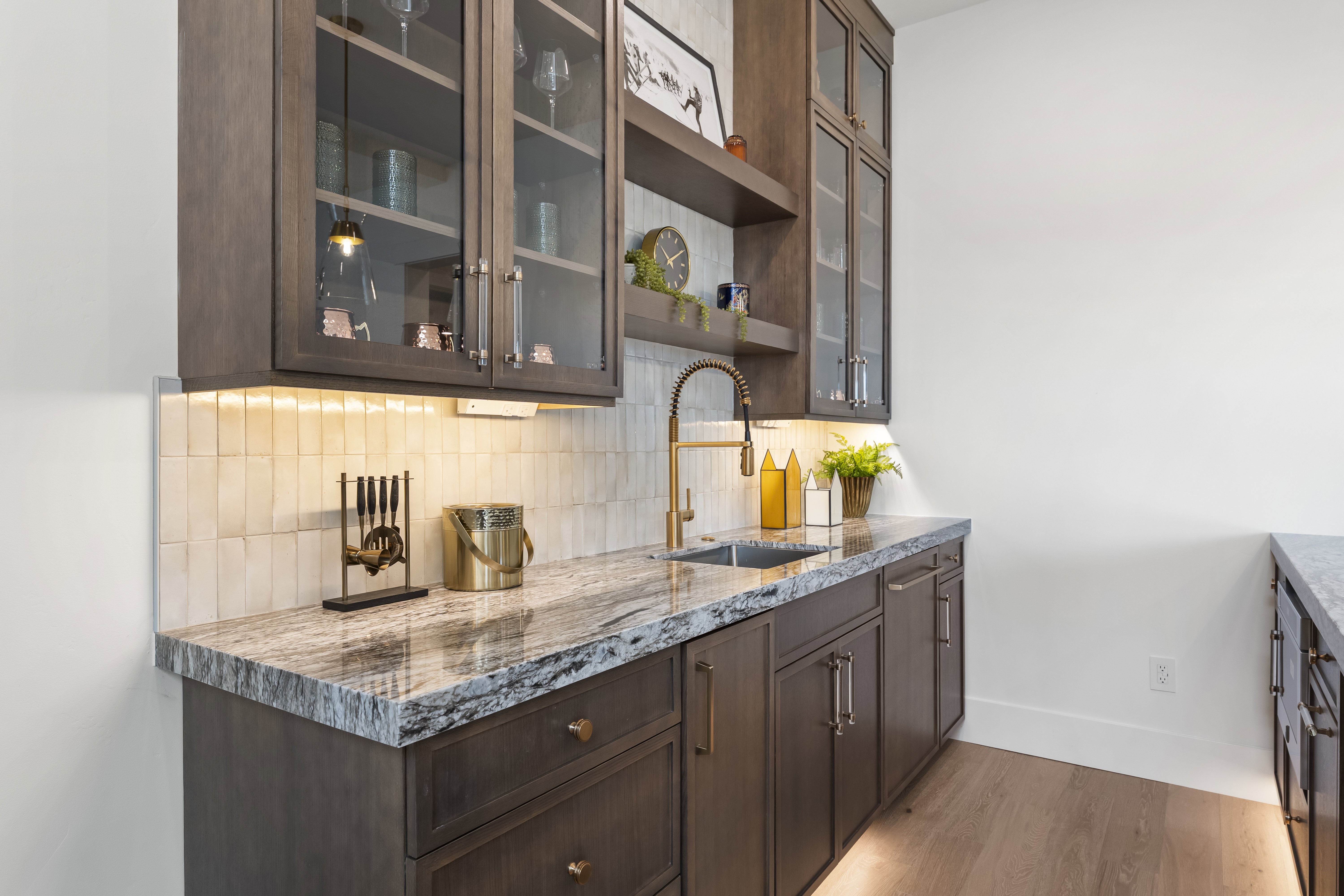 Kitchen featuring dark brown cabinetry, open shelves, light stone countertops, glass insert cabinets, and light wood finished floors
