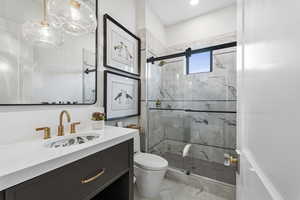 Full bathroom with vanity, a marble finish shower, and light marble finish floors