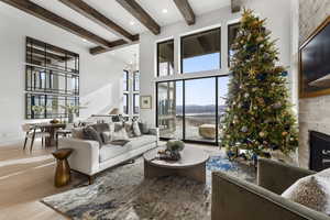Living area featuring a fireplace, a towering ceiling, wood finished floors, a chandelier, and recessed lighting