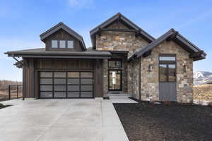 View of front of house featuring driveway, stone siding, and a garage