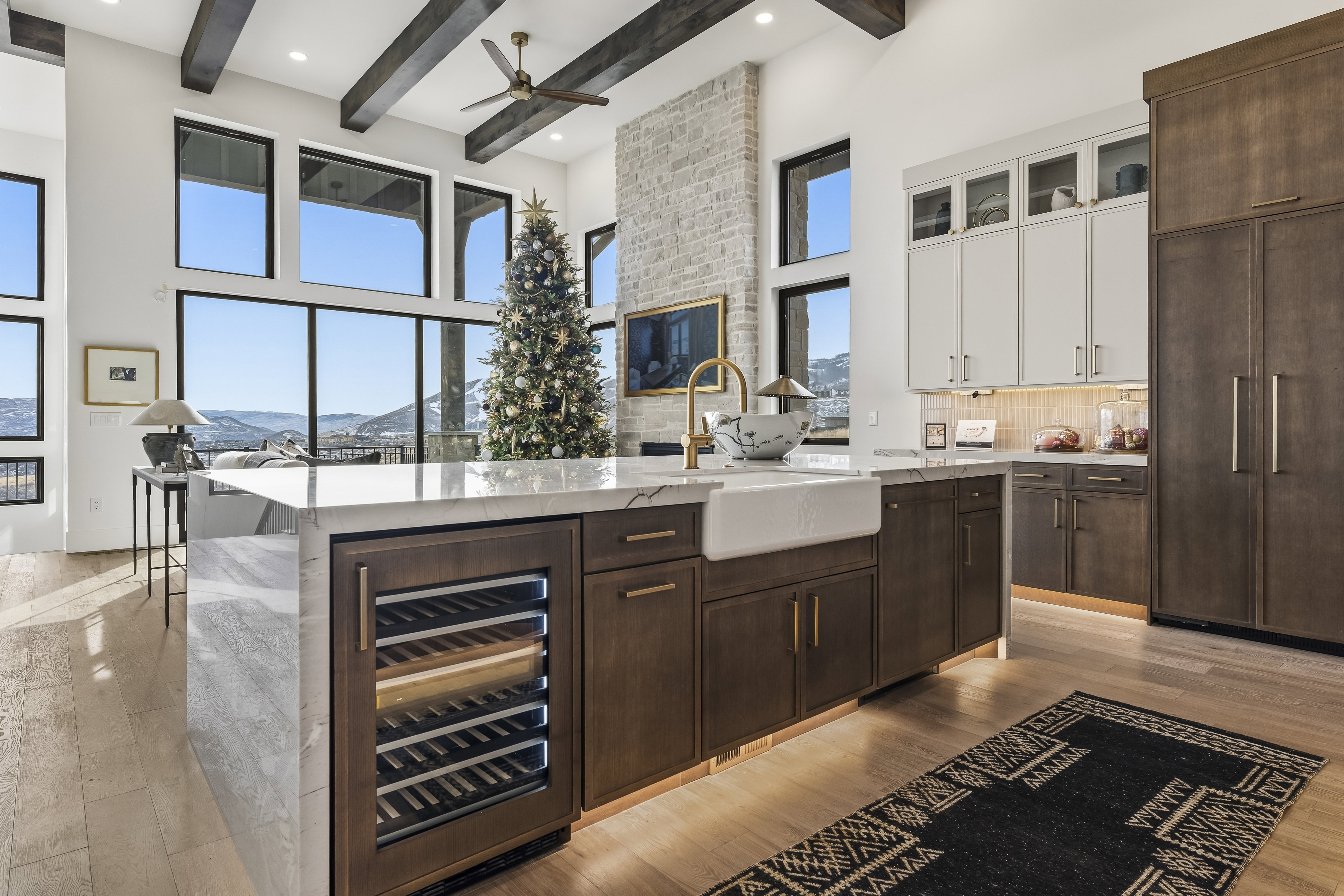 Kitchen with dark brown cabinetry, wine cooler, light stone counters, white cabinets, and tasteful backsplash