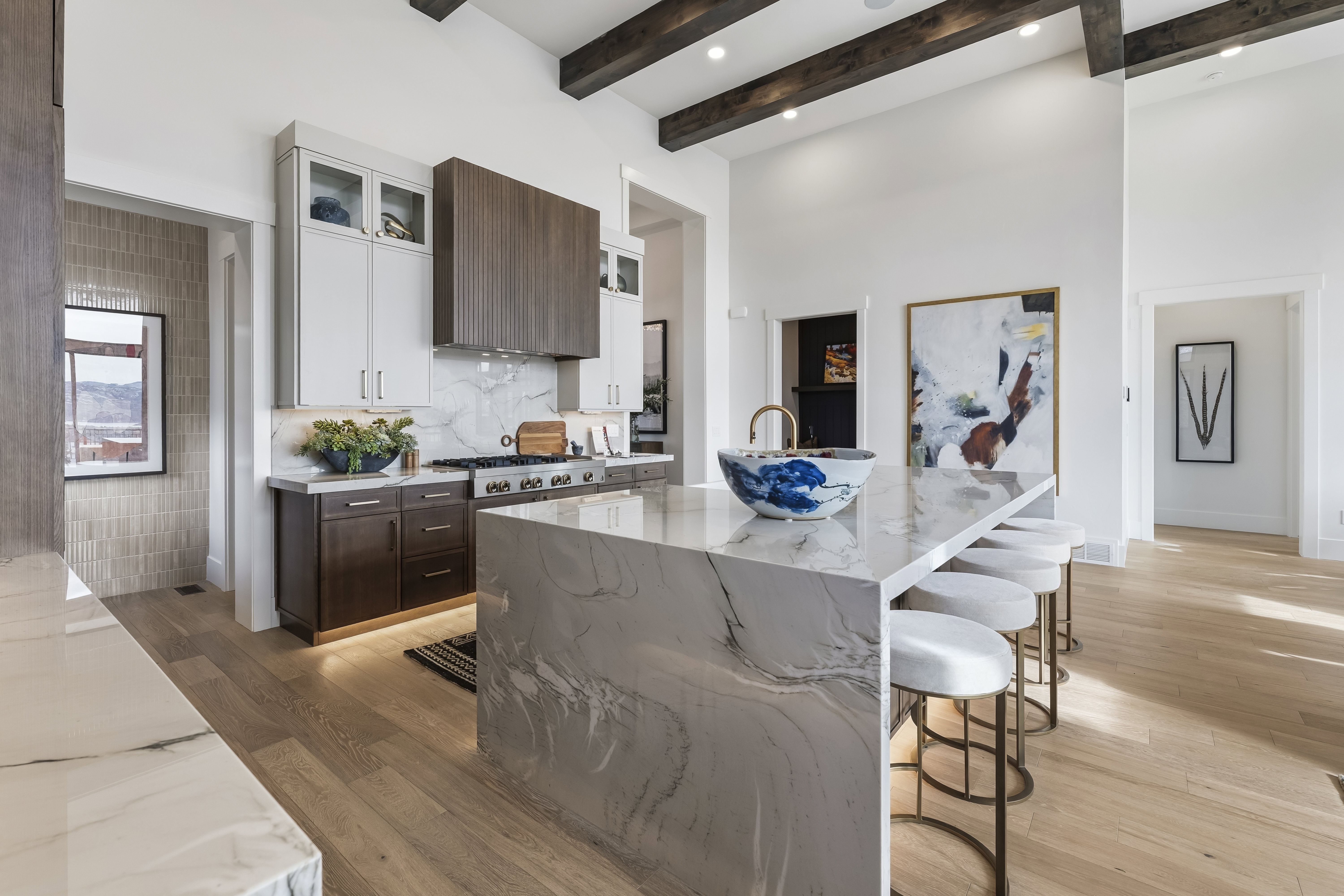 Kitchen with dark brown cabinets, light stone counters, white cabinets, a breakfast bar area, and premium range hood