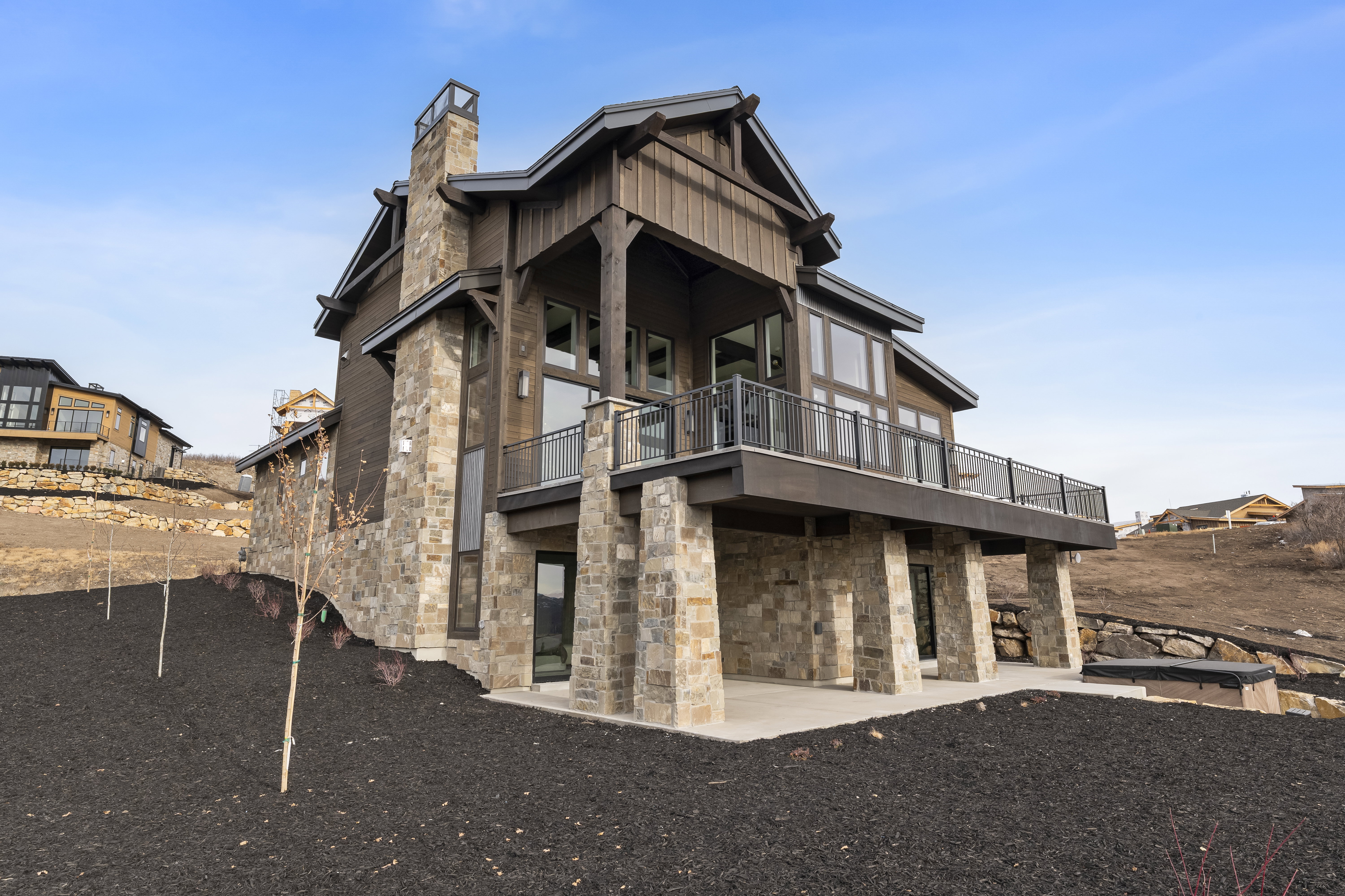Back of house with stone siding and a chimney