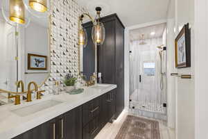 Full bathroom with double vanity, a stall shower, and backsplash