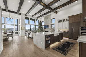 Kitchen with dark brown cabinetry, light stone counters, a high ceiling, glass insert cabinets, and backsplash