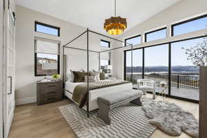 Bedroom with light wood-style flooring, a mountain view, access to exterior, a chandelier, and a high ceiling