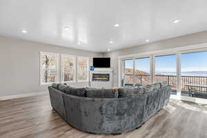 Living room with a glass covered fireplace, plenty of natural light, light wood finished floors, and recessed lighting
