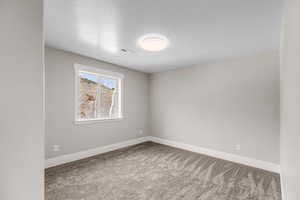Spare room with a textured ceiling and light carpet