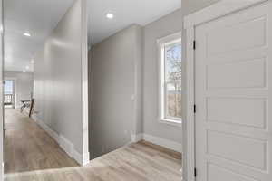 Hall with light wood-type flooring, recessed lighting, and an upstairs landing