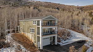 Snow covered back of property with a balcony and an attached garage