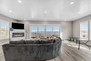 Living area featuring a glass covered fireplace, light wood-style floors, a textured ceiling, and recessed lighting