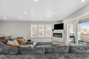 Living room featuring a glass covered fireplace, recessed lighting, and wood finished floors