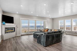 Living room with a glass covered fireplace, light wood finished floors, plenty of natural light, and recessed lighting