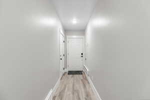 Corridor with light wood-style floors and baseboard heating
