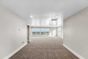 Carpeted spare room featuring a textured ceiling and recessed lighting