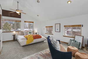Carpeted bedroom with multiple windows, high vaulted ceiling, and ceiling fan