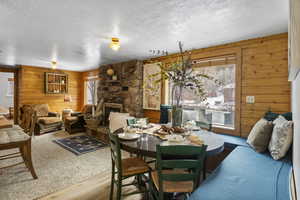 Dining space featuring wooden walls, a textured ceiling, a fireplace, and wood finished floors