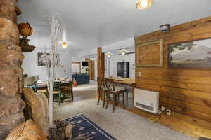 Living area featuring heating unit, wood walls, and a textured ceiling