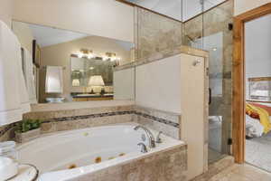 Full bath featuring a whirlpool tub, ensuite bathroom, and a shower stall