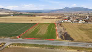 Overview of rural landscape with mountains, property parcel outlined, and rows of crops