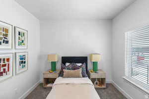 Bedroom featuring dark carpet and baseboards
